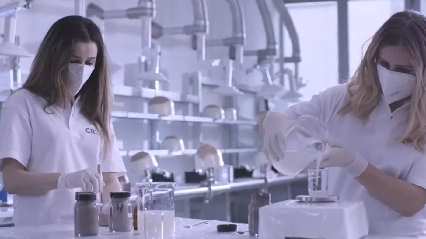 Two CRLAB specialists working in a laboratory, with scalp forms on the shelves behind them