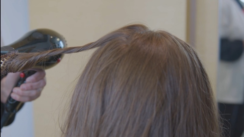 A specialist blow-drying and styling the hair of a finished CNC®